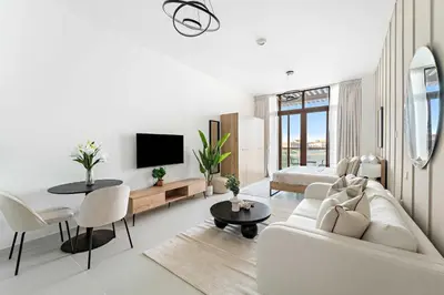 a white living room with a white couch and a tv at Silkhaus Beach Accessible Studio Palm View in Dubai