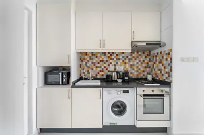 a kitchen with white cabinets and a washing machine at Silkhaus Beach Accessible Studio Palm View in Dubai