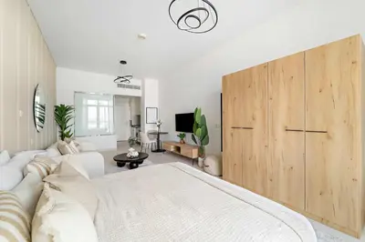 a living room with a white couch and a wooden cabinet at Silkhaus Beach Accessible Studio Palm View in Dubai