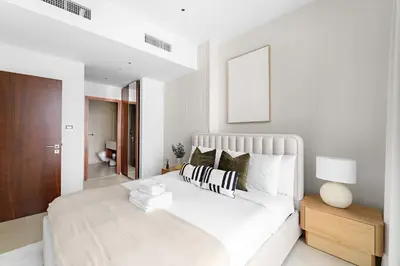 a white bedroom with a large bed and a wooden cabinet at Silkhaus Modern Dubai Marina 1BDR Marina Gate in Dubai