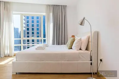 a white bed in a room with a large window at WelHome - Stylish Breathtaking 2BR Apartment in Marina in Dubai