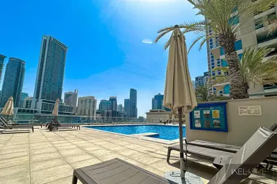 a pool with an umbrella and a palm tree at WelHome - Stylish Breathtaking 2BR Apartment in Marina in Dubai