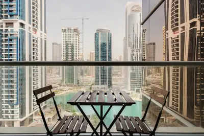 a table and chairs on a balcony with a view of a city at Blueground JLT lake view roof pool gym DXB-1546 in Dubai