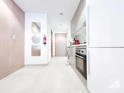 a kitchen with white floors and a white refrigerator at Charming Studio with Balcony in Azizi Riviera in Dubai