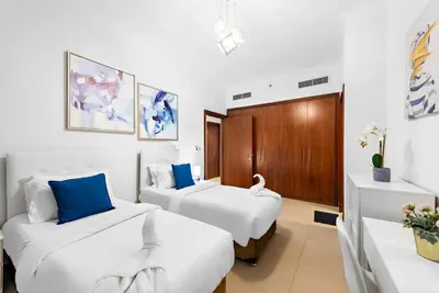 two beds in a room with white and blue at Skyline Views 2BR Near Burj Khalifa & Dubai Mall with Pool Access in Dubai