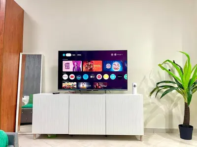 a tv on top of a white cabinet in a living room at Amazing Studio Apartment in The Crescent A Tower IMPZ in Dubai