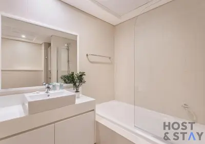 a white bathroom with a sink and a tub at Elegant Beachfront Living at Al Bateen in Dubai