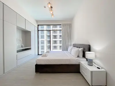 a white bedroom with a bed and a window at Wilton Terrace Charm- Stylish 1-Bedroom in MBR City With a Pool View in Dubai