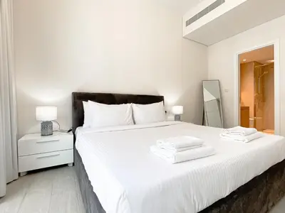 a bedroom with a white bed with towels on it at Wilton Terrace Charm- Stylish 1-Bedroom in MBR City With a Pool View in Dubai