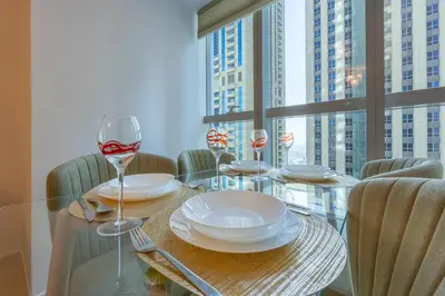 a glass table with plates and wine glasses on it at Elite Residence - Cosy One Bedroom Apartment in Dubai