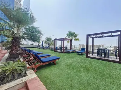a row of chaise lounges on a lawn with palm trees at Elite Residence - Cosy One Bedroom Apartment in Dubai