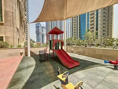 a playground with a red slide on a balcony with buildings at Elite Residence - Cosy One Bedroom Apartment in Dubai