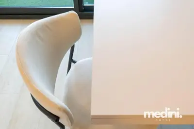 a white chair sitting next to a window at Azizi Riviera - 12min from Downtown in Dubai