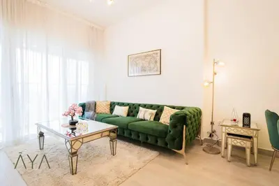a living room with a green couch and a table at Elegant 1BR Retreat with Rooftop Pool in JVC By ĀYA Boutique in Dubai