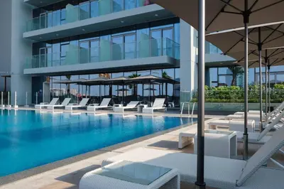 a swimming pool with lounge chairs and a building at Elegant 1BR Retreat with Rooftop Pool in JVC By ĀYA Boutique in Dubai