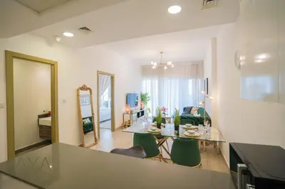 a kitchen and living room with a table and chairs at Elegant 1BR Retreat with Rooftop Pool in JVC By ĀYA Boutique in Dubai