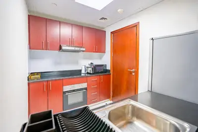 a kitchen with red cabinets and a sink at RH - Marina View Getaway, Spacious One-Bedroom with Terrace in Dubai Marina in Dubai