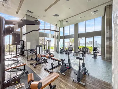 a gym with a lot of exercise equipment and large windows at Luxurious 2BR Home with Stunning Marina Skyline View in Dubai