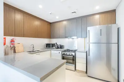 a kitchen with white appliances and wooden cabinets at Luxurious 2BR Home with Stunning Marina Skyline View in Dubai