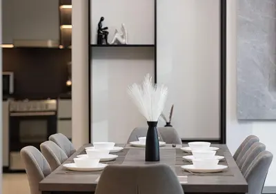 a dining room table with chairs and a vase with feathers at Downtown Luxe, steps to Burj Khalifa 4BDR in Dubai