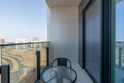 a chair on a balcony with a view of a city at Cozy Studio - Dubai Land -Tiger V Tower in Dubai