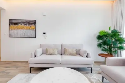 a white living room with a couch and a plant at 1 Bedroom - Ahad Residence - Business Bay - Dubai in Dubai