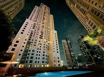 a tall building with a pool in front of it at Stunning Sea & Palm View 2BR, Steps from JBR Beach & Waterfront in Dubai