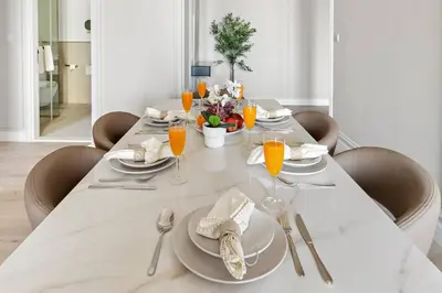 a dining room table with a white tablecloth and glasses of orange juice at Stunning Sea & Palm View 2BR, Steps from JBR Beach & Waterfront in Dubai