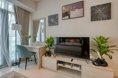 a living room with a flat screen tv on a wooden entertainment center at Beachfront Studio Right by Nakheel Mall in Dubai