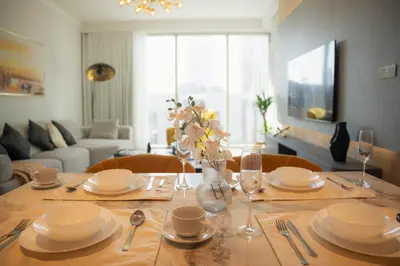 a dining room table with plates and a vase of flowers at Luxury 2 Bedroom Poolside Haven in Dubai Creek Harbour in Dubai