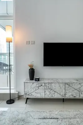 a living room with a television on a white wall at ShoresInn - Marvelous Marina View In Dubai in Dubai