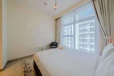 a bedroom with a white bed and a large window at Modern 2BDR Apartment I Dubai Hills I City View I Mulberry at Park Heights in Dubai