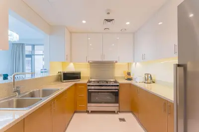 a kitchen with white cabinets and a sink and a stove at Beautiful 2BR I Heart of BLVD I Downtown Dubai in Dubai