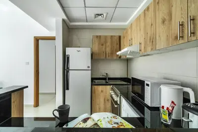 a kitchen with a white refrigerator and wooden cabinets at ShoresInn - Radiant 1BR in Dubai Marina in Dubai