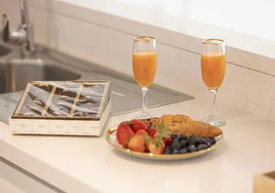 two glasses of orange juice and a plate of fruit at Stylish Burj khalifa view 5 Star 4BD Apartment in Downtown with Dubai Mall access - Brand New Apartment in Dubai