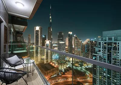 a balcony with a view of a city at night at High Floor Apartment in 5 Star Hotel with Infinity Pool Burj View Gym Spa Sauna in Dubai