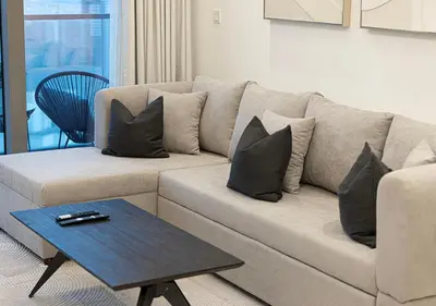 a living room with a couch with pillows and a table at High Floor Apartment in 5 Star Hotel with Infinity Pool Burj View Gym Spa Sauna in Dubai
