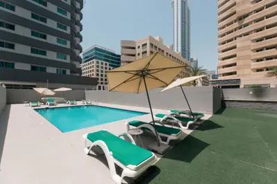 a pool with lounge chairs and an umbrella at Skyline Studio Apartment with Balcony in Dubai Marina in Dubai