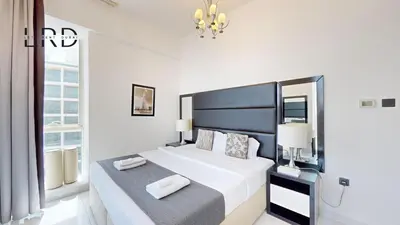 a white bedroom with a large bed and a chandelier at Modern & Spacious 2BR Apartment in Dubai