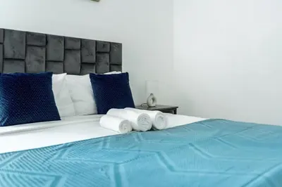 a bed with blue and white pillows and towels on it at ShoresInn - Tranquil 1BR in Dubai Marina in Dubai