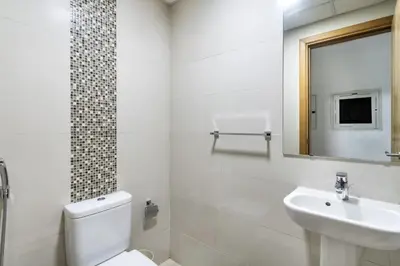 a white bathroom with a toilet and a sink at ShoresInn - Tranquil 1BR in Dubai Marina in Dubai