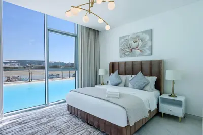 a bedroom with a large bed and a pool at Lagoonview 2BR District One in Dubai