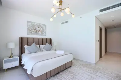 a bedroom with a large bed and a chandelier at Lagoonview 2BR District One in Dubai