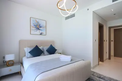 a white bedroom with a bed and a couch at Lagoonview 2BR District One in Dubai