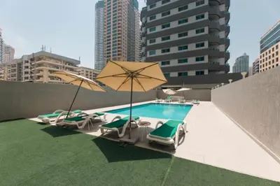 a pool with chairs and umbrellas on a rooftop at Studio with Sunset Views at Dubai Marina in Dubai