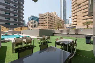 a rooftop patio with tables and chairs and a pool at Studio with Marina Breeze in Dubai