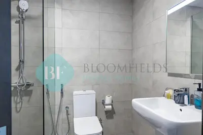 a bathroom with a shower and a toilet and a sink at Bloomfileds Cozy Stu In Unistate Supreme Residence in Dubai