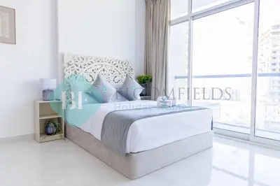 a bedroom with a large bed and a large window at Bloomfileds Cozy Stu In Unistate Supreme Residence in Dubai