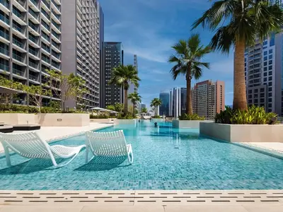 a swimming pool with two chairs and palm trees at Cute studio in The Sterling by Omniyat in Dubai