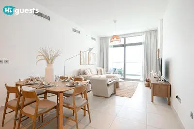 a white living room with a table and chairs at HiGuests - Premier Beachfront Stylish 2BR Apt and Maid Room in Dubai